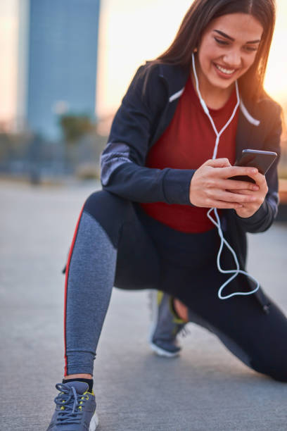 istock Modern young woman with cellphone making pause during jogging / exercise. 1305816079