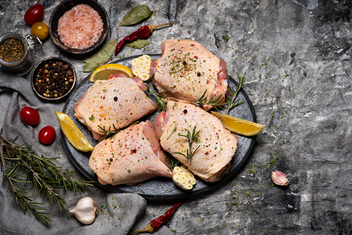 Raw chicken thighs meat with cooking ingredients on a table top view