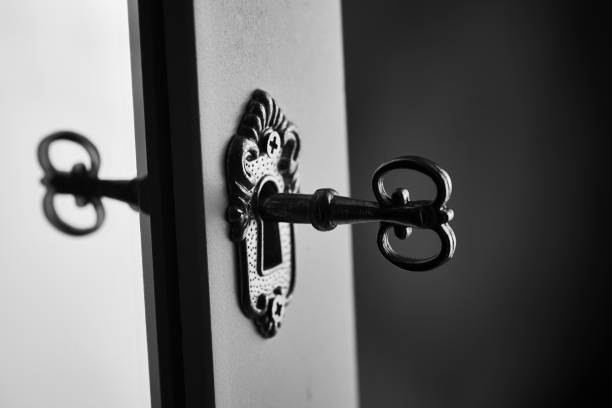 Old key in keyhole reflecting in the mirror. Security concept. Black and white macro photo with copy space.