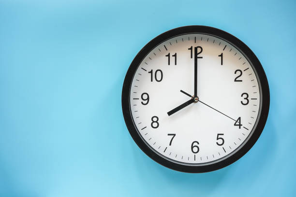 istock Classic black and white analog clock on blue background at Eight o'clock with copy space 1305817908