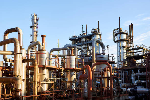istock Old distillation column towers and reactors under blue evening sky background at chemical plant. Exterior of silver metal rusty enterprise with copyspace. 1305818766