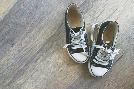 Black and white sneakers on a wood floor. Copy space.