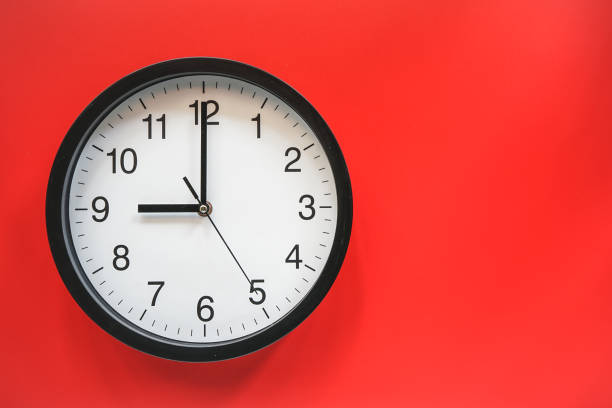 istock Classic black and white analog clock on red background at Nine o'clock with copy space 1305820262