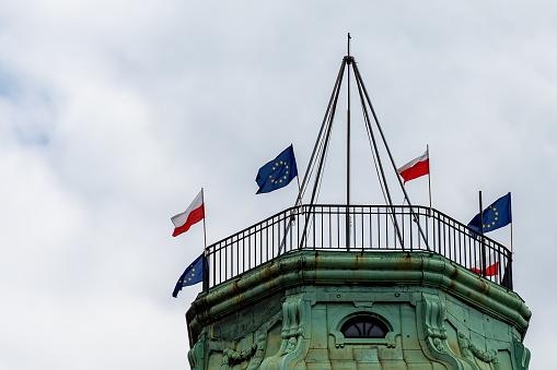 Wroclaw, Poland - May 03 2020: Top of old tenement house with Polish flags and european union flags