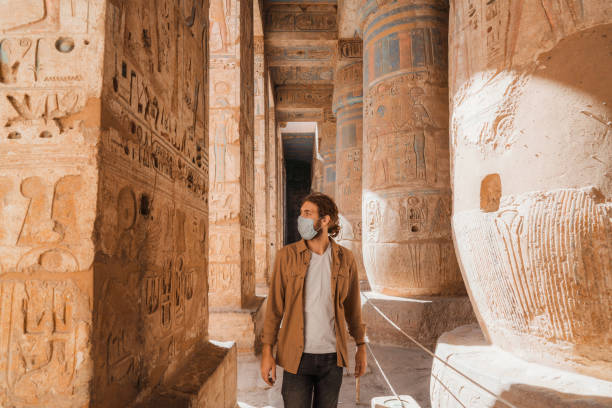 Man walking in the ancient Egyptian temple in Luxor Young Caucasian man walking in the ancient Egyptian temple in Luxor during Covid-19 pandemic hieroglyphics photos stock pictures, royalty-free photos & images