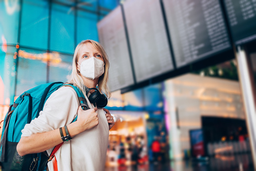 Portrait of a young woman checks the arrivals and departures board at the airport. She wears a face mask for protection during a Coronavirus pandemic.
New normal lifestyle for public transport after Covid-19
