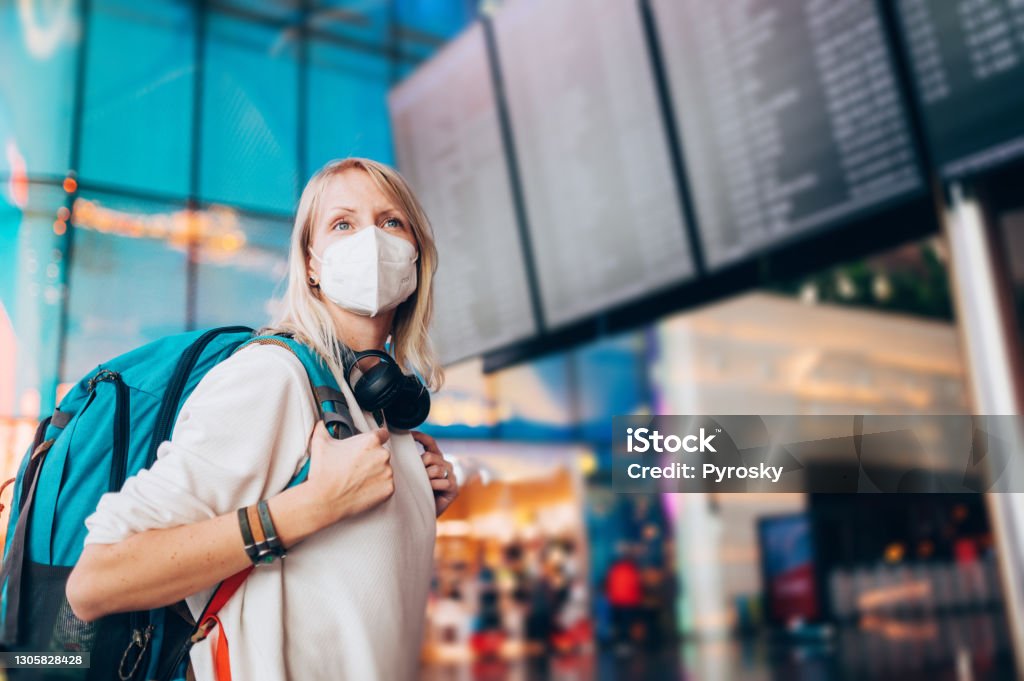 Happy To Travel Again Portrait of a young woman checks the arrivals and departures board at the airport. She wears a face mask for protection during a Coronavirus pandemic.
New normal lifestyle for public transport after Covid-19 Travel Stock Photo