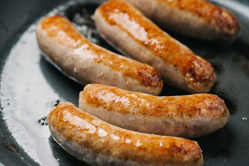 Closeup of Italian sausage links frying in a pan in Frederick, MD, United States
