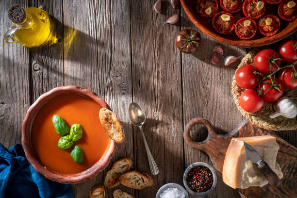 istock Tomato soup with roasted tomatoes, basil, ingredients  and toasted bread on rustic wood 1305831607