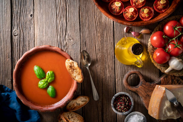 istock Tomato soup with roasted tomatoes, basil, ingredients  and toasted bread on rustic wood 1305831657