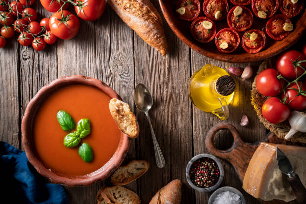 istock Tomato soup with roasted tomatoes, basil, ingredients  and toasted bread on rustic wood 1305831712