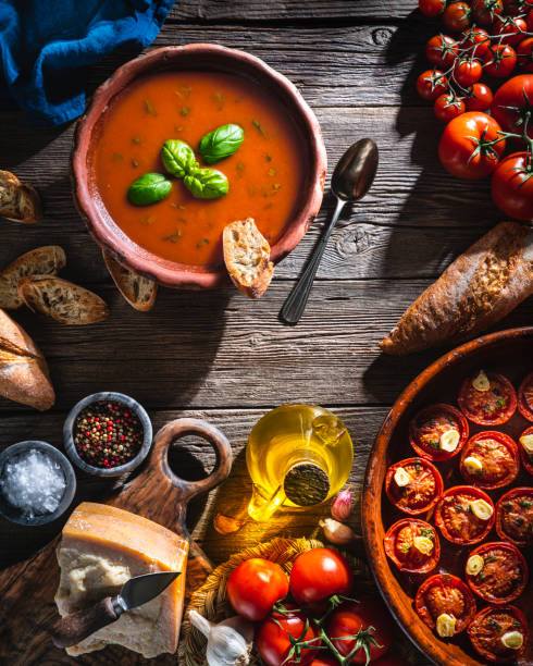 istock Tomato soup with roasted tomatoes, basil, ingredients  and toasted bread on rustic wood 1305831739