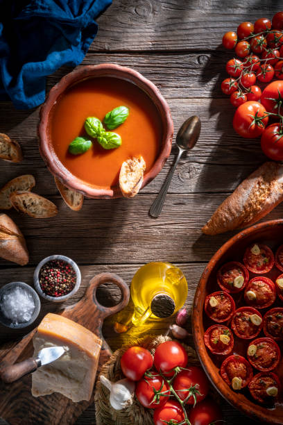 istock Tomato soup with roasted tomatoes, basil, ingredients  and toasted bread on rustic wood 1305831767