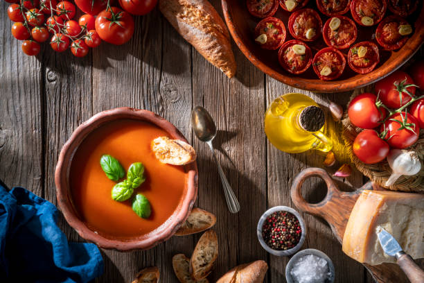 istock Tomato soup with roasted tomatoes, basil, ingredients  and toasted bread on rustic wood 1305831800
