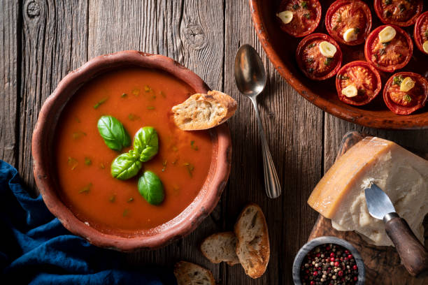 istock Tomato soup with roasted tomatoes, basil, ingredients  and toasted bread on rustic wood 1305831846