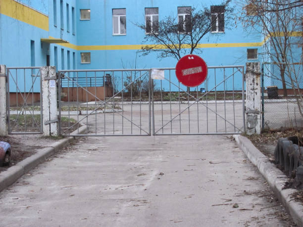 istock tattered gate with a no entry sign and a paper note, a blue building and a courtyard behind it 1305832474