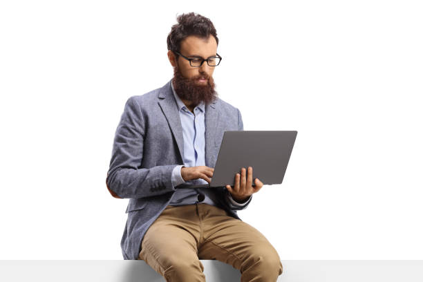 istock Bearded man with on a laptop sitting on a panel 1305834536