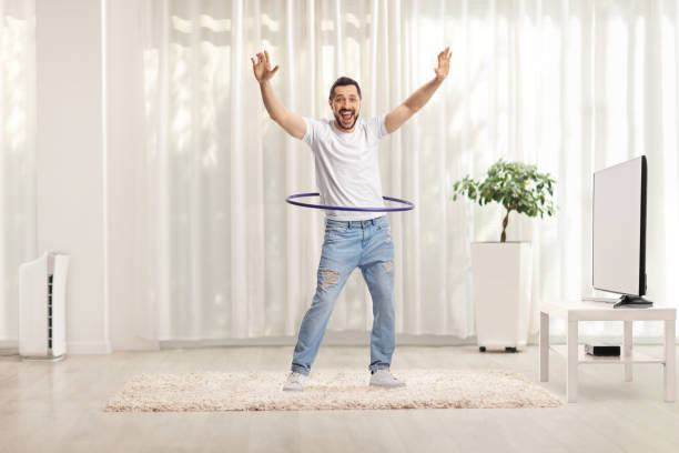 istock Cheerful man spinning a hula hoop and smiling at home 1305834551
