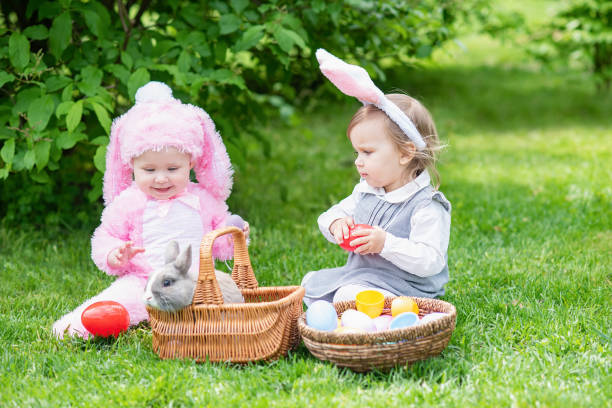 istock Children play with real rabbit. Laughing child at Easter egg hunt with pet bunny. 1305835120