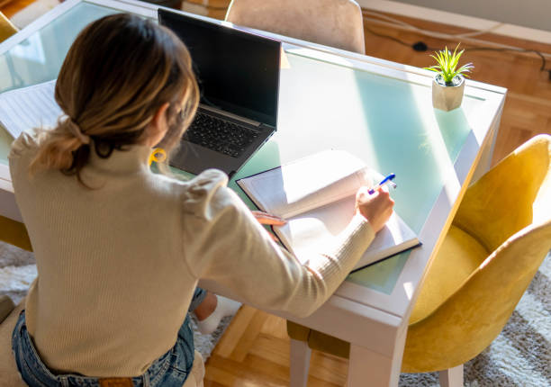 istock Hard Working Young beautiful Woman is writing and using laptop. She is working from home office 1305835790