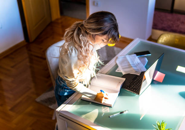 istock Hard Working Young beautiful Woman is writing and using laptop. She is working from home office 1305836440