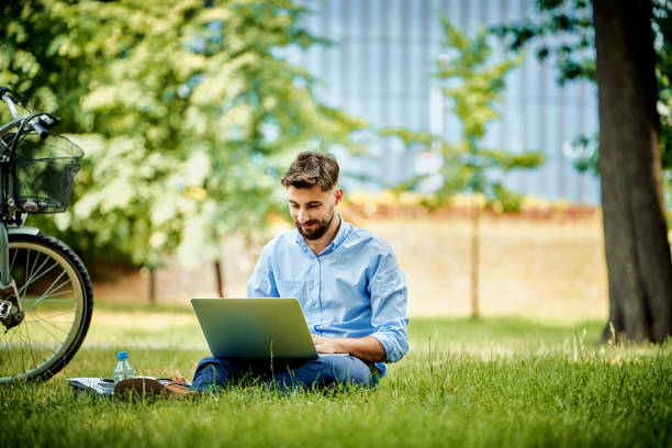 istock Young business man working on laptop in park 1305839395
