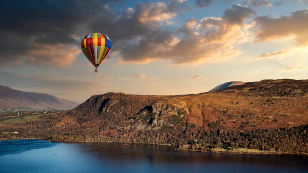 Hot air balloon flying over stunning Derwent Water landscape in Lake District during Summer sunset Hot air balloon flying over Derwentwater landscape in Lake District during Summer sunset keswick stock pictures, royalty-free photos & images