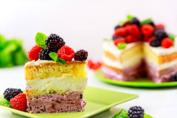 Sponge cake with vanilla cream and fresh berries on white table.