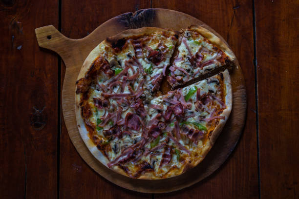 istock Meat pizza on wooden board 1305844066