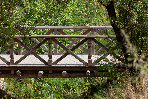 Wooden pedestrian bridge over a deep ravine summer day