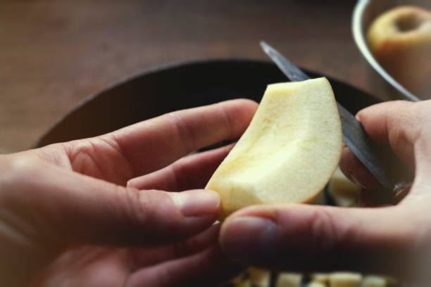 Cutting an apple into pieces Human hand with a knife, cutting an apple in pieces for baking an apple pie fruit carving stock pictures, royalty-free photos & images