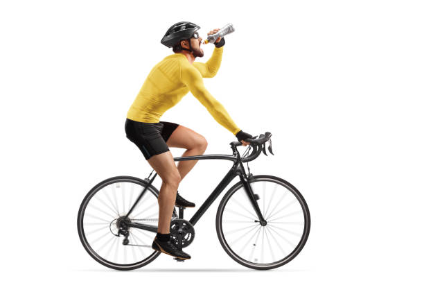 Profile shot of a male athlete riding a bike and drinking from a bottle Profile shot of a male athlete riding a bike and drinking from a bottle isolated on white background sportsman professional sport side view horizontal stock pictures, royalty-free photos & images