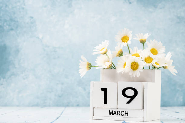 istock White cube calendar for march decorated with daisy flowers over blue with copy space 1305850032