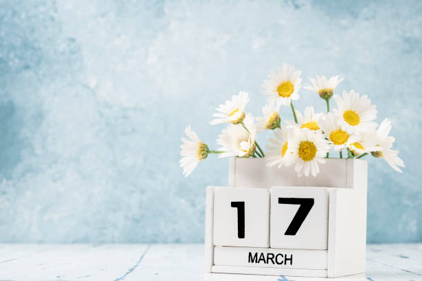 istock White cube calendar for march decorated with daisy flowers over blue with copy space 1305850033