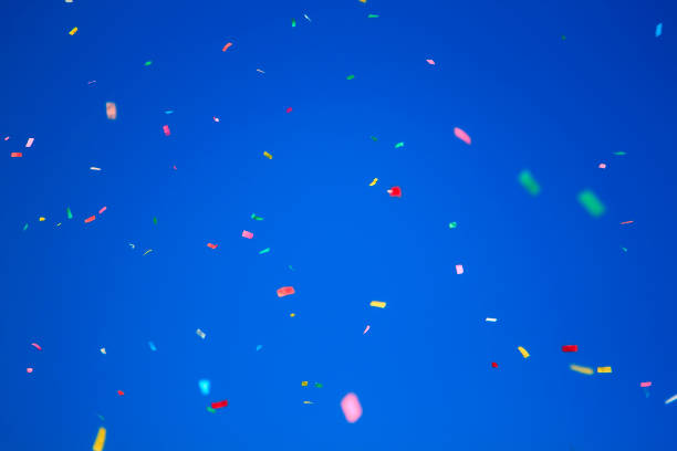 istock multicolored confetti on clear blue sky background. Concept of h 1305850141