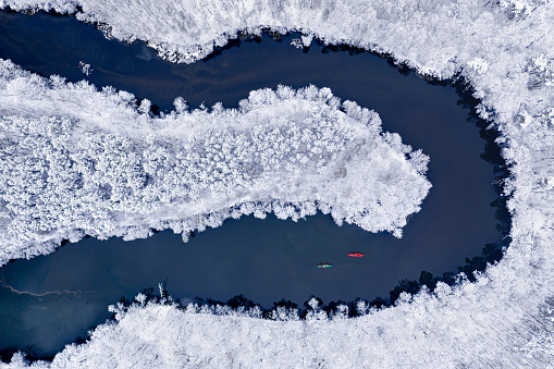 Kayaking on winter river. Extreme Sport in winter. Kayaking between snowy forest. Aerial view of nature in Poland