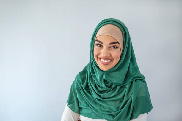 Portrait young muslim woman in pgreen headscarf smile Portrait young muslim woman in pgreen headscarf smile.Happy moment concept. Headshot of a beautiful Muslim female model in a casual wear and hijab isolated on grey background hijab photos stock pictures, royalty-free photos & images