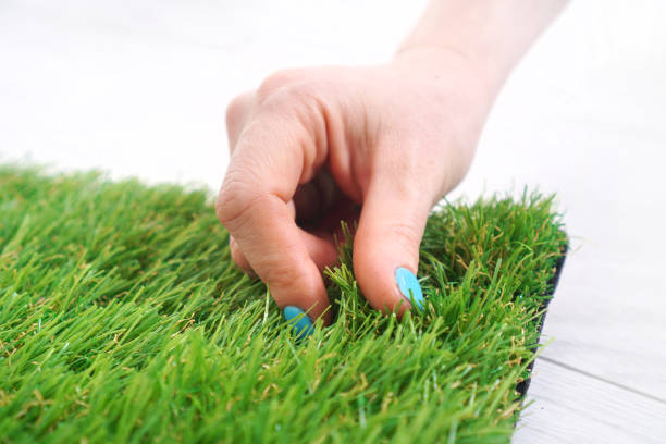 istock Woman's hand touches the artificial turf 1305853526