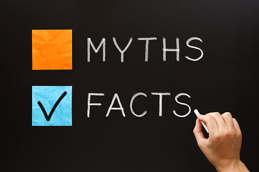 Hand writing Myths or Facts concept with white chalk on blackboard. Choose the Facts over the Myths.