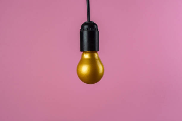 istock Creative composition. A golden incandescent lamp on a pink background. 1305854845