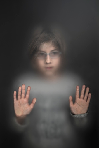 View of scared child through frosted glass