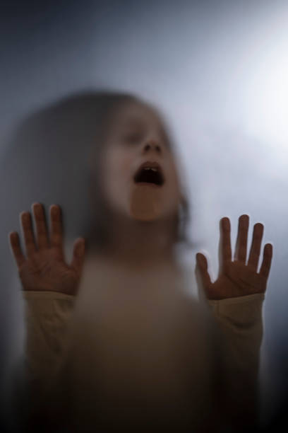 istock View of scared child through frosted glass 1305854949