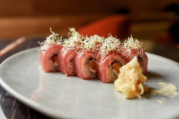 istock Close up of appetizing sushi rolls decorated with sprouts served on white plate with ginger. Healthy gourmet raw cuisine 1305854956