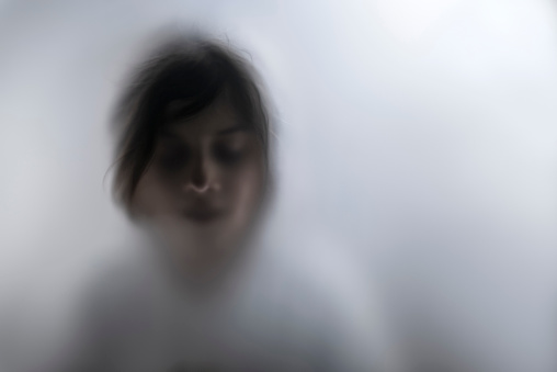 View of scared child through frosted glass