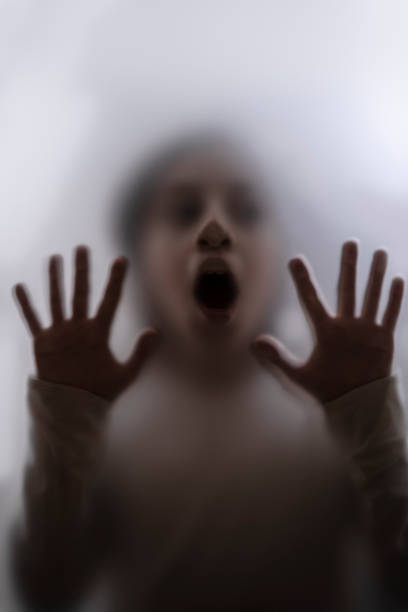istock View of scared child through frosted glass 1305855650