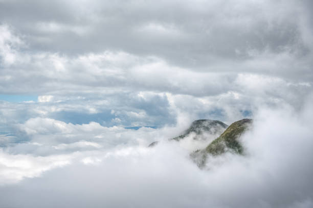 Photo of Two mountain peaks piercing through the clouds