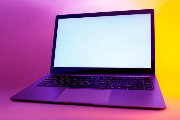 istock Slim modern laptop with white screen on the background creative light. Mockup in colorful bright neon UV blue and purple lights. 1305857983