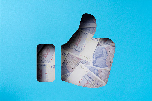 Money heap under paper cutout thumbs up icon, British pound