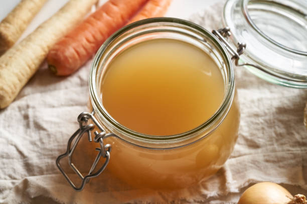 istock A jar of bone broth with vegetables in the background 1305859549