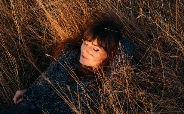 istock Beautiful Young Woman Enjoying the Sunlight While Lying in High Grass 1305860176